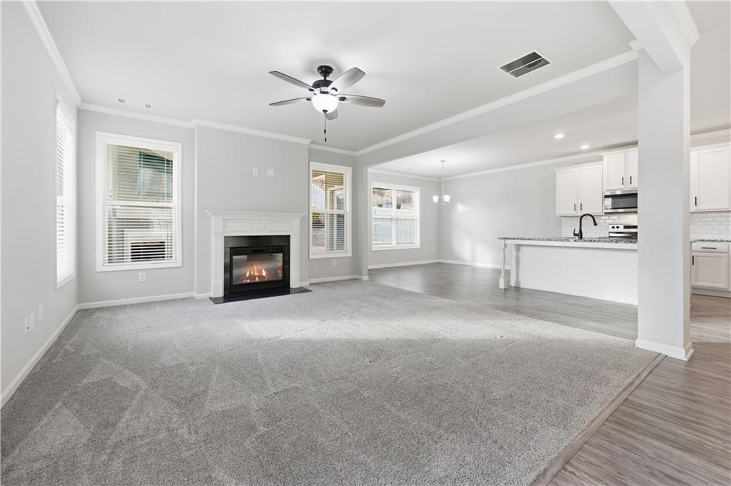 3244 Hawthorne Path Braselton, GA 30517 - Photo 5 of 48 a view of a livingroom with a fireplace a ceiling fan and windows