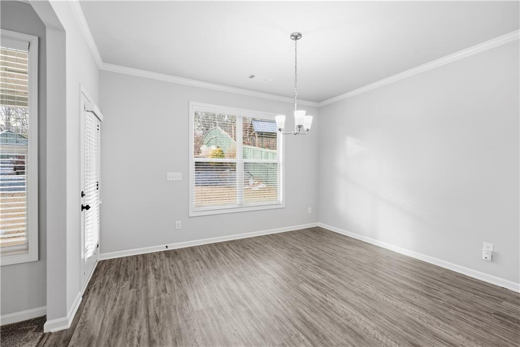 3244 Hawthorne Path Braselton, GA 30517 - Photo 9 of 48 an empty room with wooden floor a ceiling fan and windows