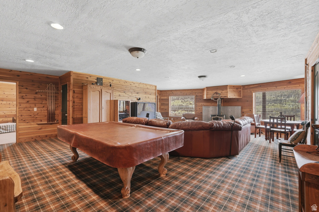 6 Beaver Springs Rancheros Oakley, UT 84055 - Photo 29 of 68 Spacious entertainment room featuring wood-paneled walls, a plaid carpet, recessed lighting, and a prominent wood-burning stove