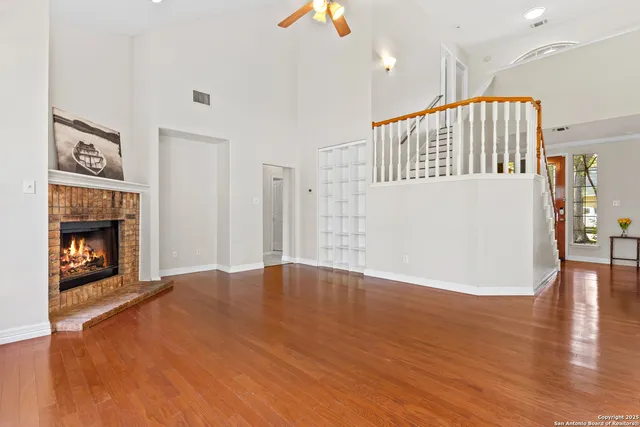 a view of an empty room with wooden floor fireplace and a window