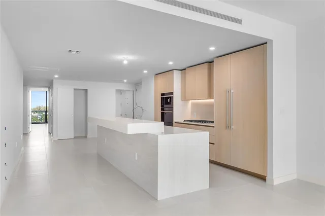 a view of a big room with wooden floor and a kitchen