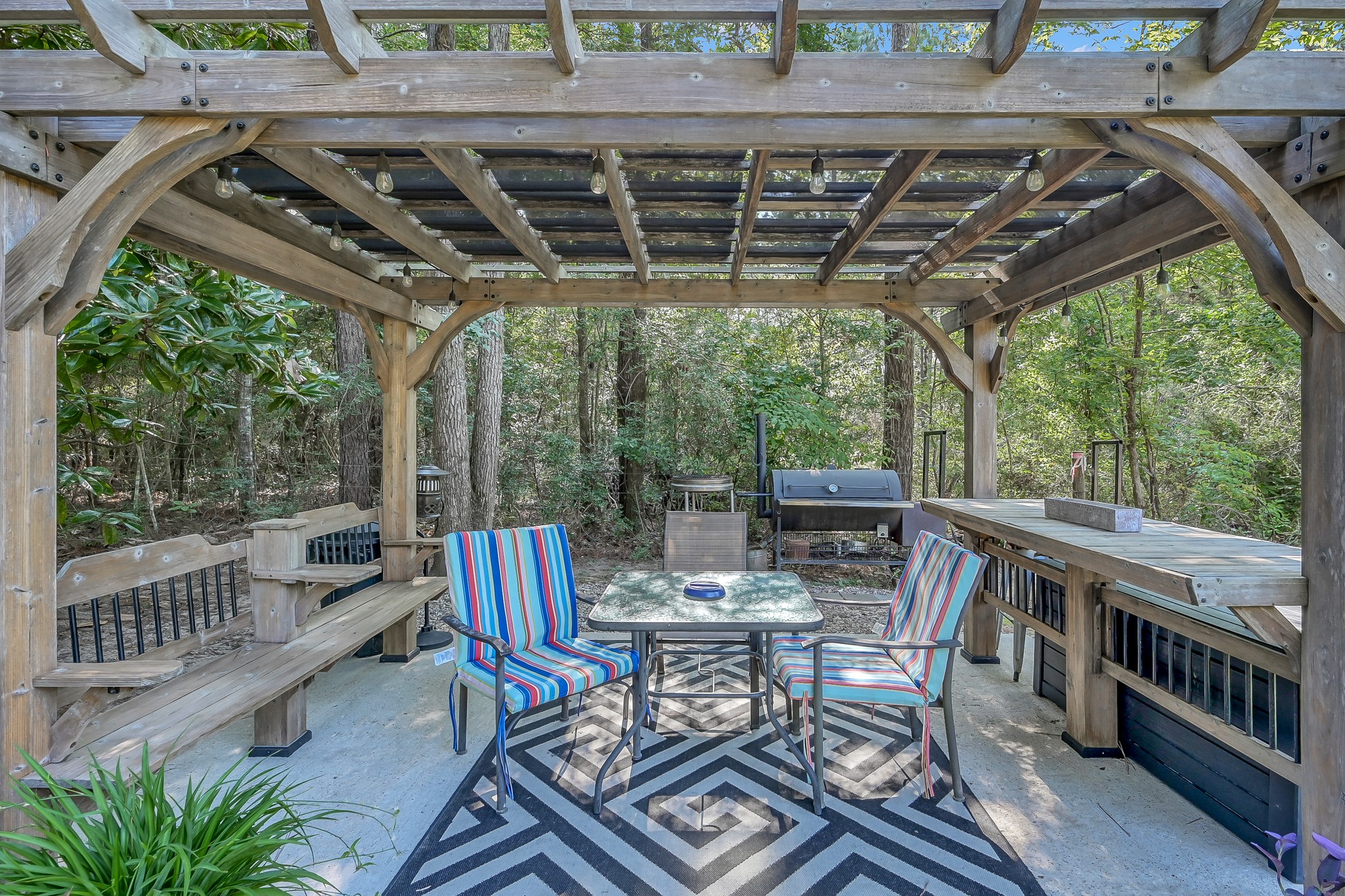 261 Franklyn Road Coldspring, TX 77331 - Photo 19 of 19 Covered pergola patio with built-in seating, grilling area, and plenty of space for entertaining while enjoying peaceful wooded views.