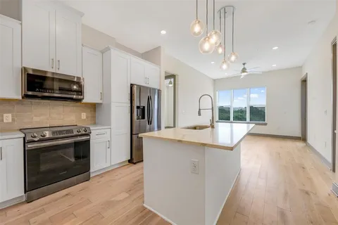 a kitchen with stainless steel appliances granite countertop a stove a refrigerator a sink a microwave oven with cabinets and wooden floor