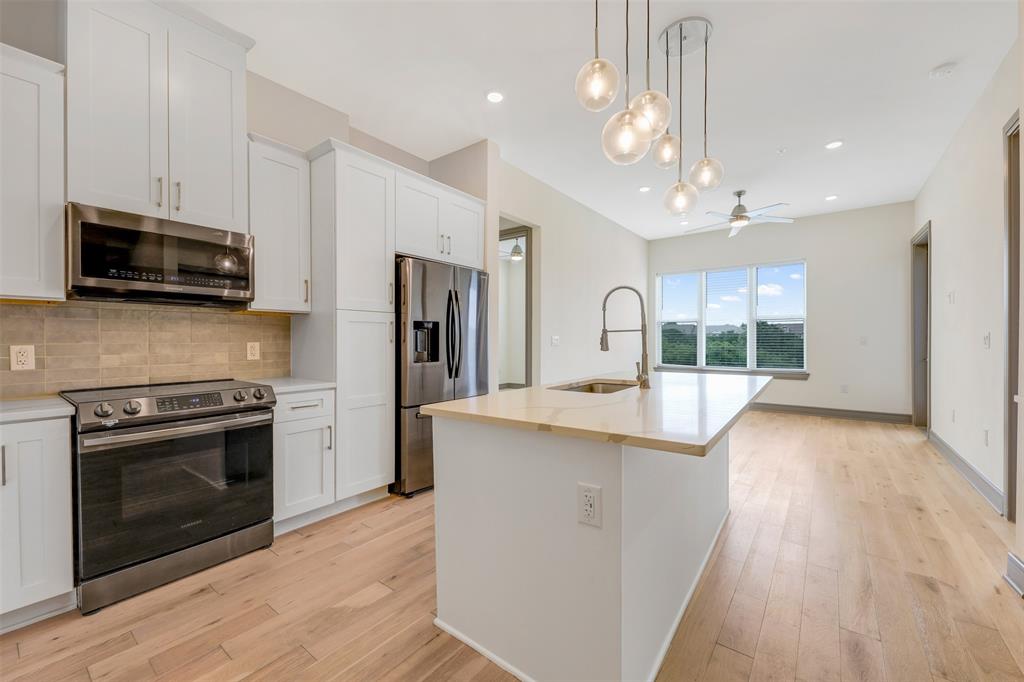 a kitchen with stainless steel appliances granite countertop a stove a refrigerator a sink a microwave oven with cabinets and wooden floor