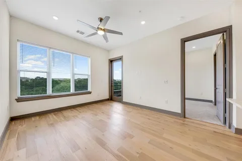 a view of an empty room with a window and wooden floor