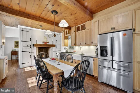 a kitchen with stainless steel appliances a refrigerator a stove a dining table and chairs with wooden floor