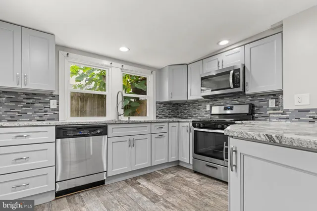 a kitchen with granite countertop a sink stainless steel appliances and window