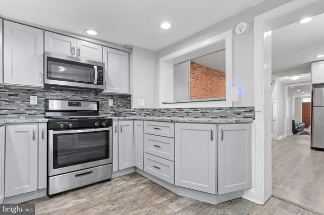 a kitchen with stainless steel appliances white cabinets a stove a sink and a microwave