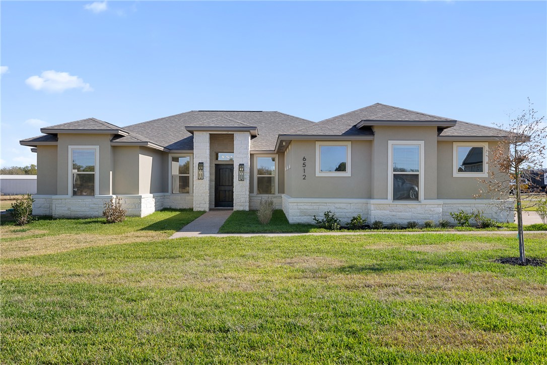 6512 Agave Court Bryan, TX 77808 - Photo 8 of 42 Prairie-style home featuring stone siding, a front yard, a shingled roof, and stucco siding