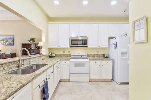 a kitchen with granite countertop a sink stove and refrigerator