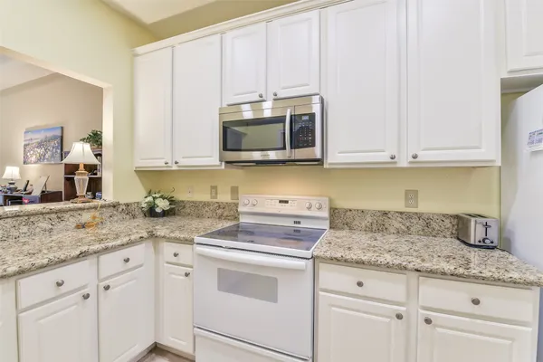 a kitchen with granite countertop white cabinets and a sink