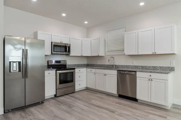 a kitchen with kitchen island granite countertop a sink cabinets and stainless steel appliances