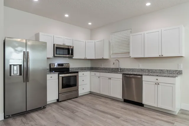 a kitchen with kitchen island granite countertop a sink cabinets and stainless steel appliances