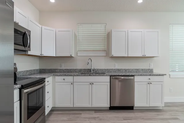 a kitchen with stainless steel appliances granite countertop a sink a stove and a microwave