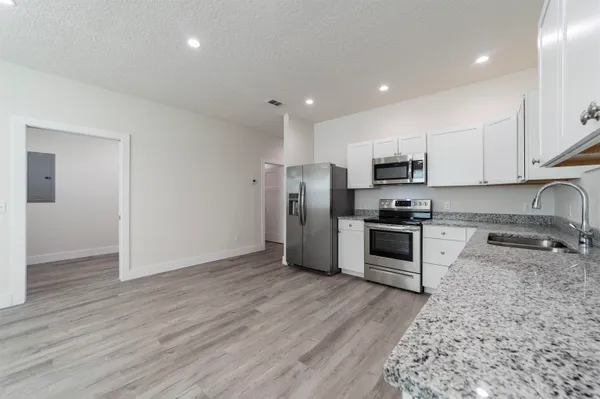 a kitchen with granite countertop a refrigerator and a stove top oven