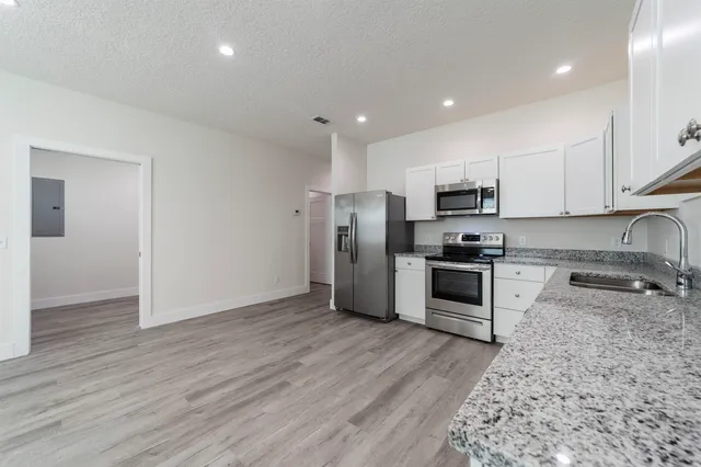 a kitchen with granite countertop a refrigerator and a stove top oven