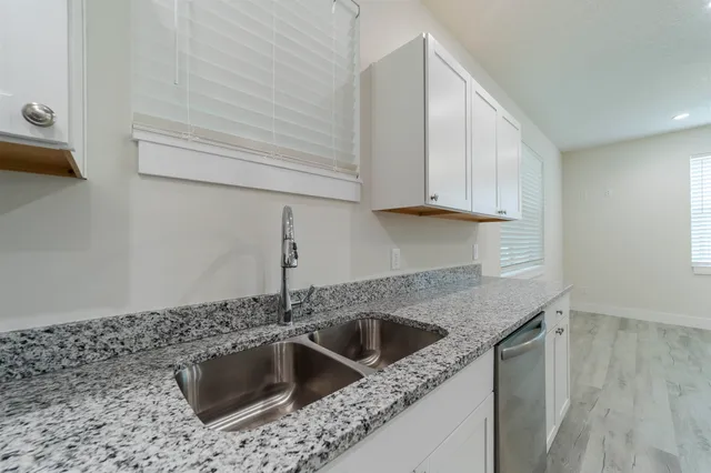 a kitchen with stainless steel appliances granite countertop a sink and a white cabinets