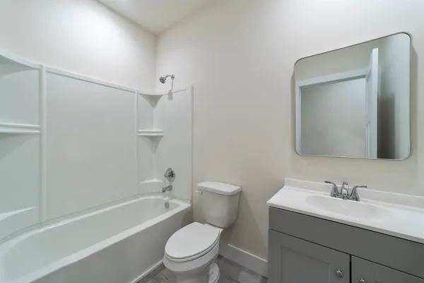 a bathroom with a toilet a sink a mirror a bathtub and vanity