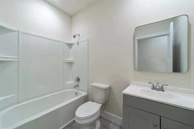 a bathroom with a toilet a sink a mirror a bathtub and vanity