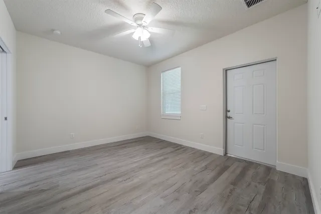 an empty room with wooden floor and ceiling fan