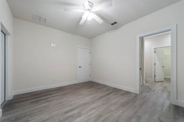 a view of a room with wooden floor and a ceiling fan