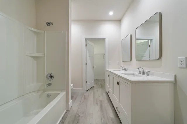 a bathroom with a double vanity sink mirror and bathtub