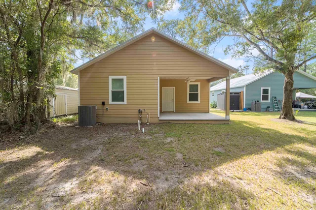 a view of a house with a yard and large tree
