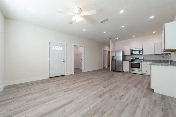 an empty room with stainless steel appliances kitchen island hardwood floor and cabinets