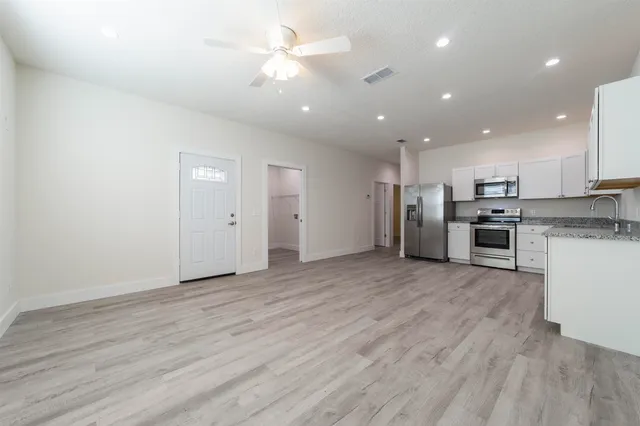an empty room with stainless steel appliances kitchen island hardwood floor and cabinets