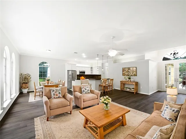 a living room with furniture kitchen view and a wooden floor