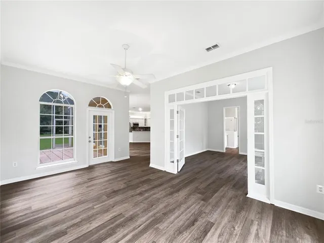 an empty room with wooden floor and windows