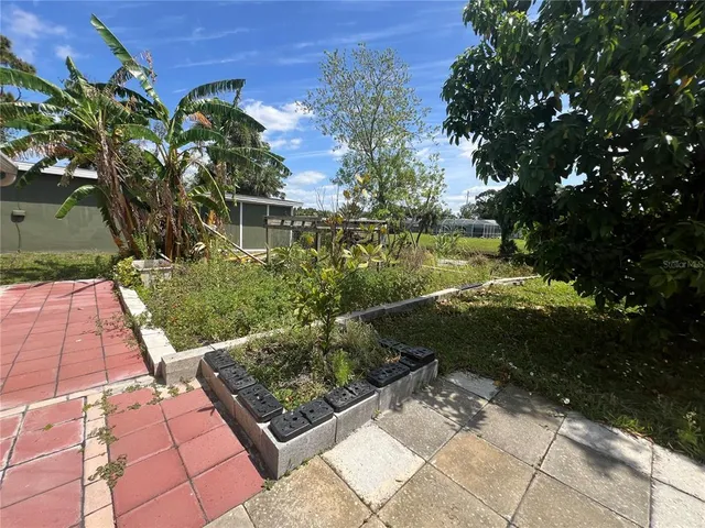a view of a garden with a bench in front of the house