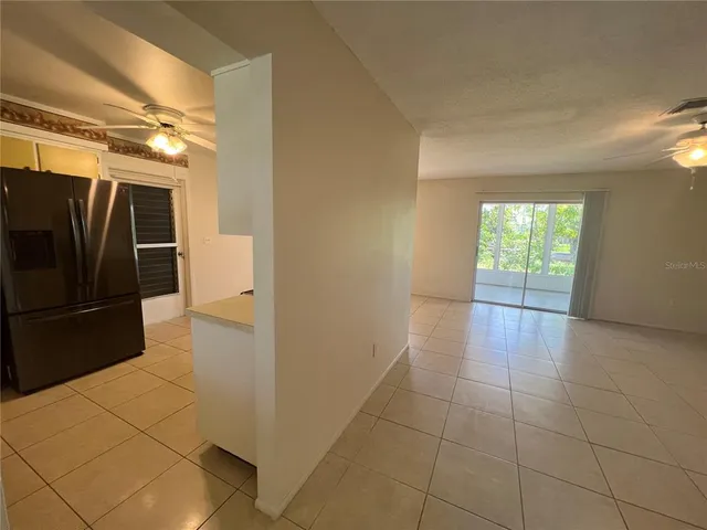 a view of a refrigerator in kitchen and an empty room in wooden floor