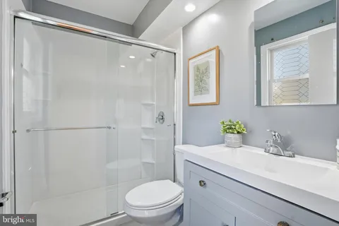 a bathroom with a granite countertop sink a toilet a shower and a mirror