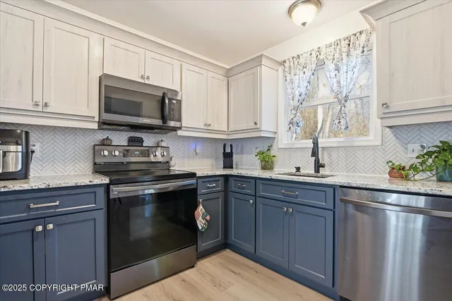 a kitchen with granite countertop a sink cabinets stainless steel appliances and a window