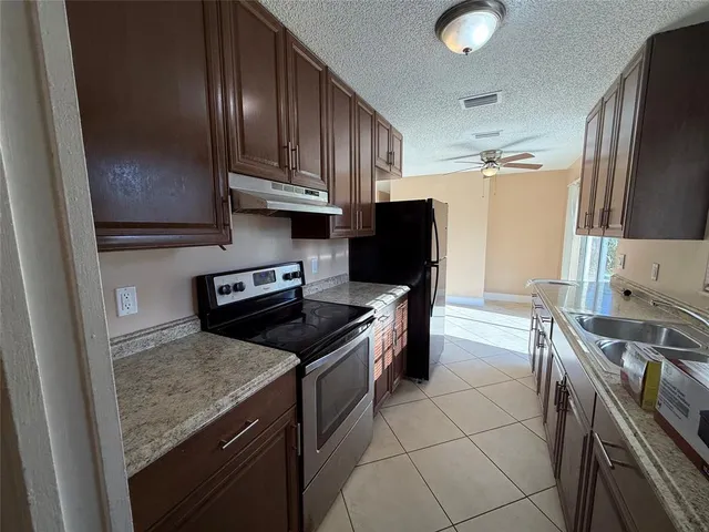 a kitchen with granite countertop a sink stove and refrigerator