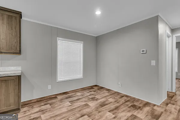 a view of a kitchen with kitchen island wooden floor center island stainless steel appliances and cabinets