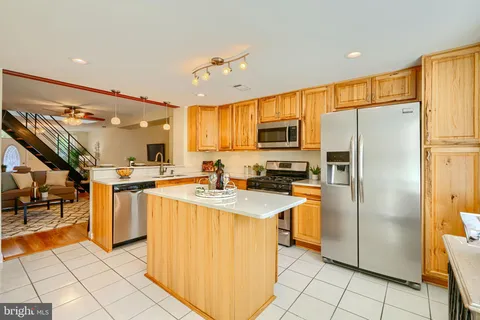 a kitchen with stainless steel appliances granite countertop a refrigerator oven a sink dishwasher and white cabinets with wooden floor