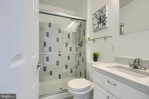 a bathroom with a granite countertop sink toilet and shower