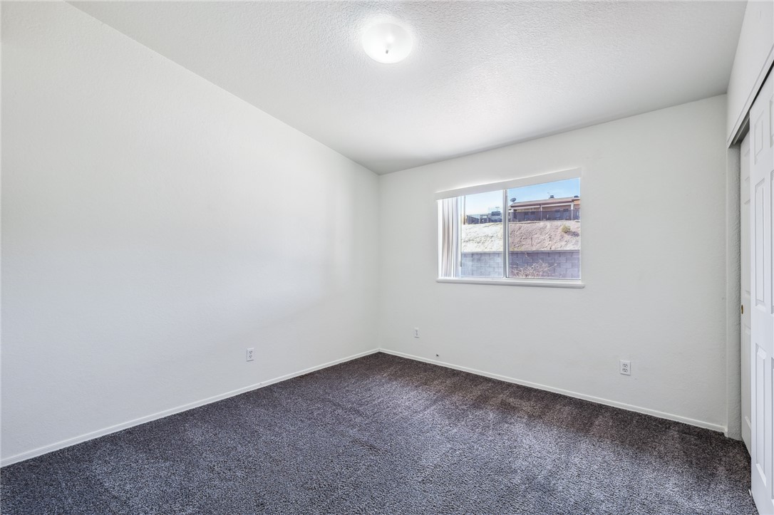 2524 South Ridge Avenue Bullhead City, AZ 86429 - Photo 42 of 64 Unfurnished room with dark carpet, baseboards, and a textured ceiling