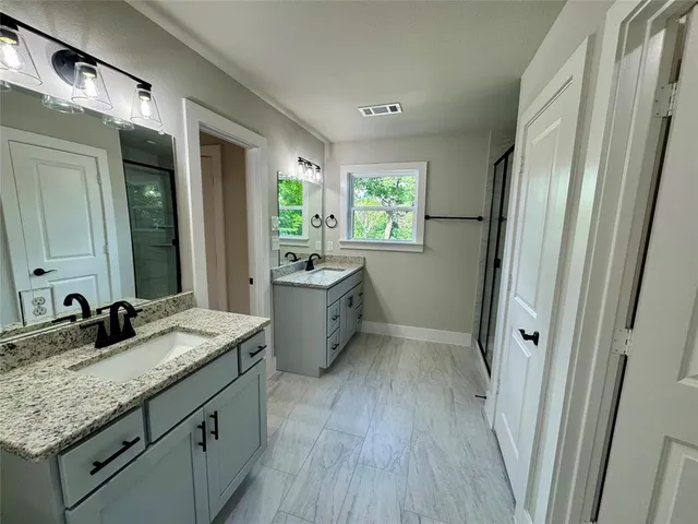 a bathroom with a granite countertop sink toilet and shower a mirror