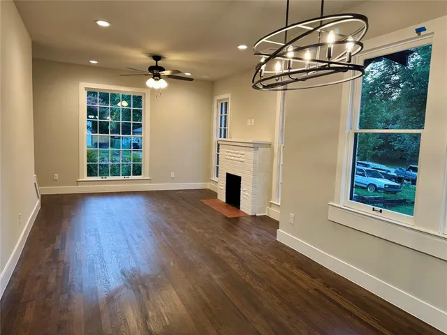 an empty room with wooden floor cabinet and windows