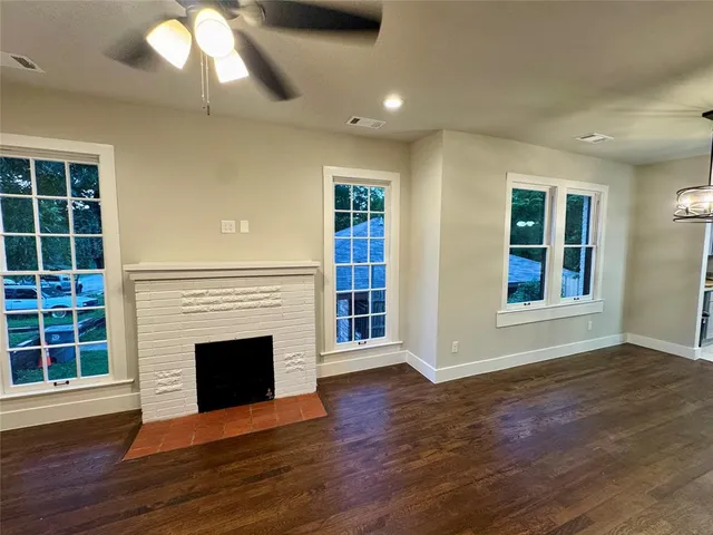 an empty room with wooden floor a fireplace and windows
