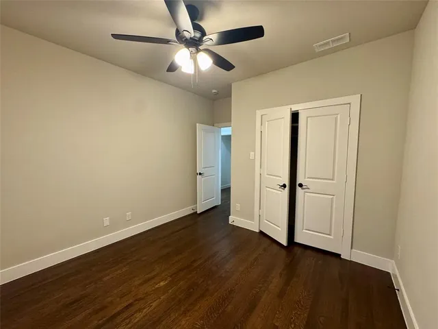 an empty room with wooden floor closet and windows