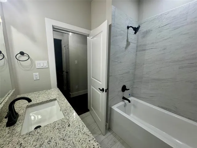 a bathroom with a granite countertop sink a toilet and bathtub