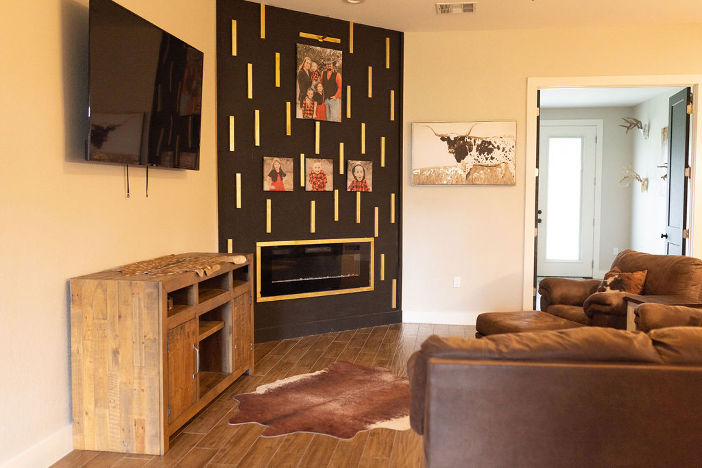 111 Powder Ridge Luling, TX 78648 - Photo 3 of 22 A striking black accent wall with golden accents surrounds a modern fireplace, anchoring this comfortable living area.