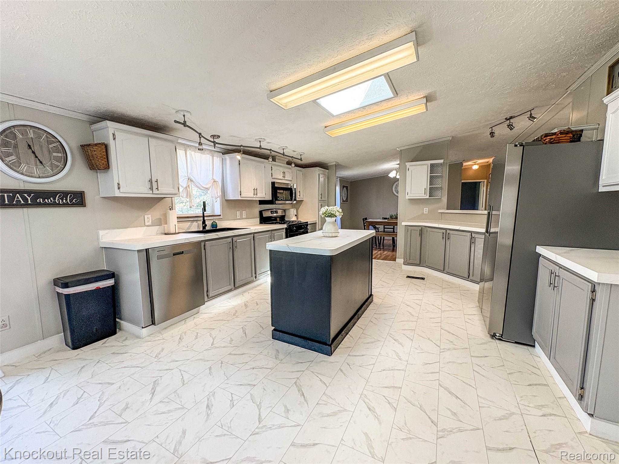 7760 Bell Road Birch Run, MI 48415 - Photo 21 of 68 Kitchen featuring white upper cabinetry, gray lower cabinetry, a dark-toned island with a white countertop, and white-patterned tile flooring