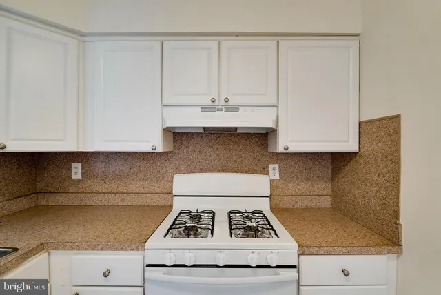 a kitchen with granite countertop white cabinets and white appliances