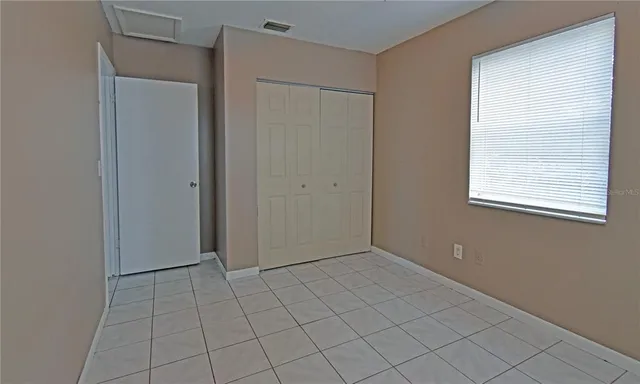 a view of an empty room with window and chandelier fan