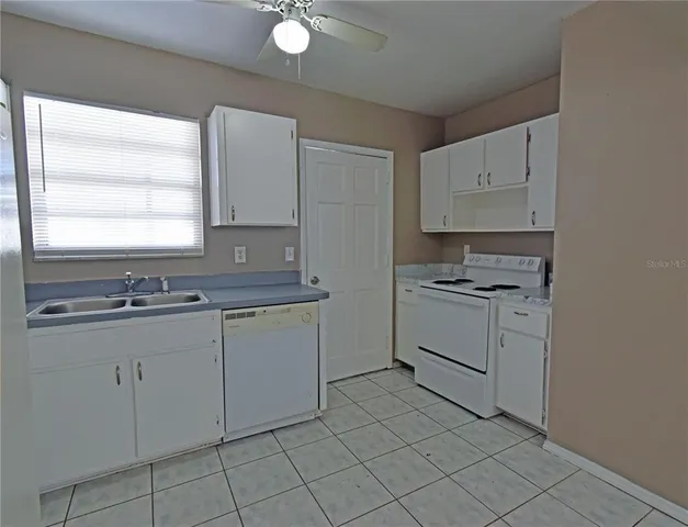 a kitchen with white cabinets appliances and a window